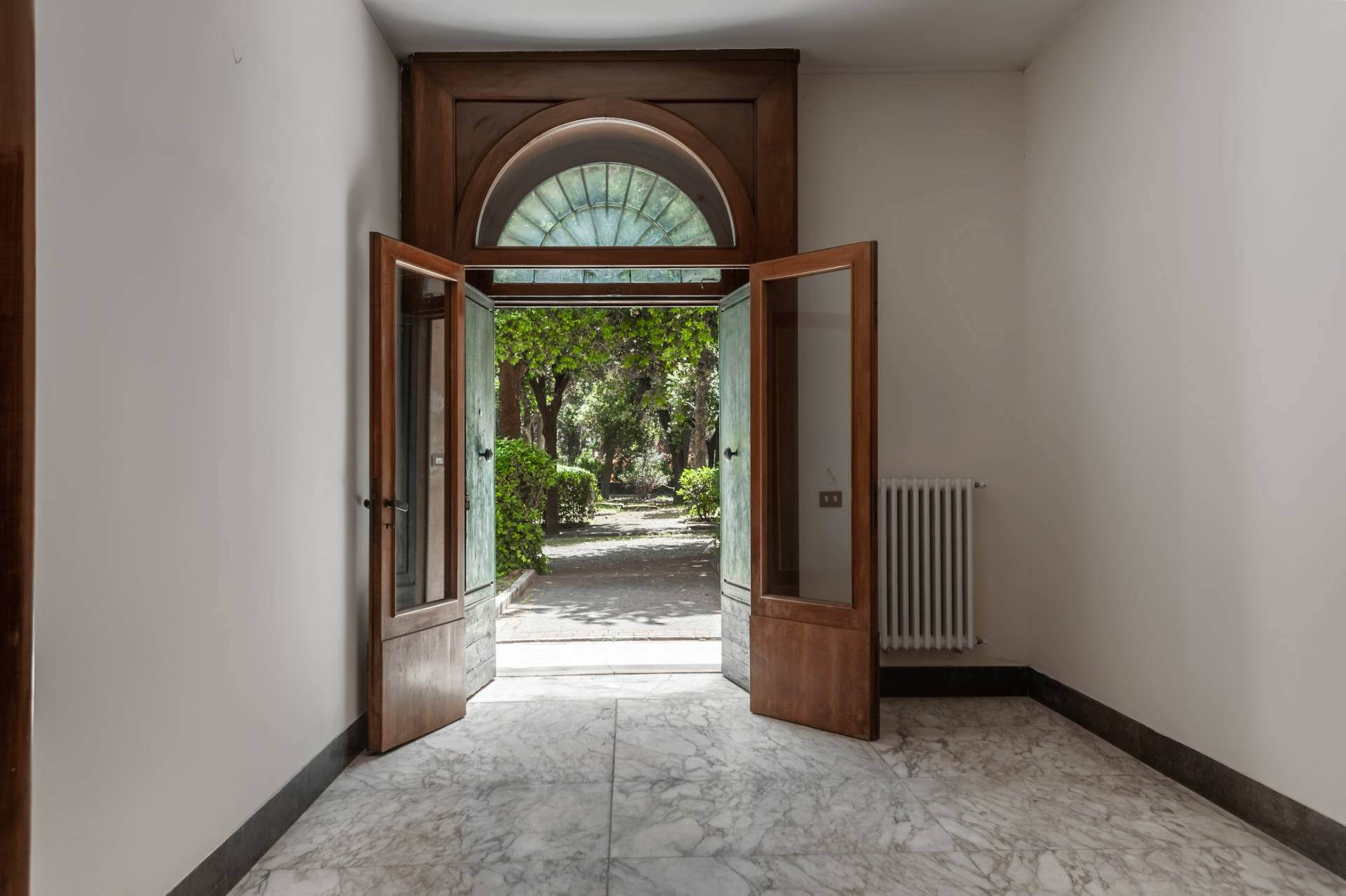 Ingresso villa storica con doppia porta lignea e vista giardino interno in proprietà di pregio