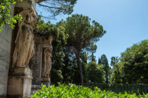 Facciata storica di villa con dettagli scultorei in pietra e vegetazione lussureggiante nel giardino privato